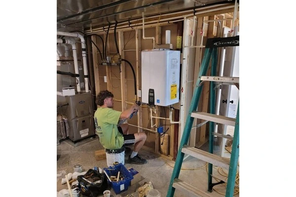 Plumber installing a wall-mounted water heater in a basement